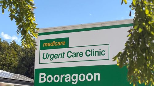 Booragoon Medicare Urgent Care Clinic sign in green and white with tree branches framing the sign