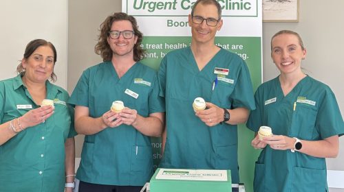 Booragoon UCC team smile whilst holding branded cupcakes in front of a branded pull up banner